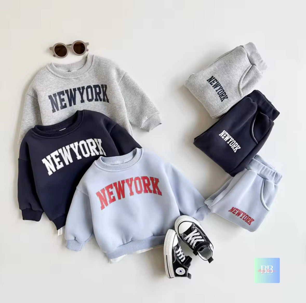 Collection of 'New York' themed clothing items including sweatshirts and shorts on a white background.