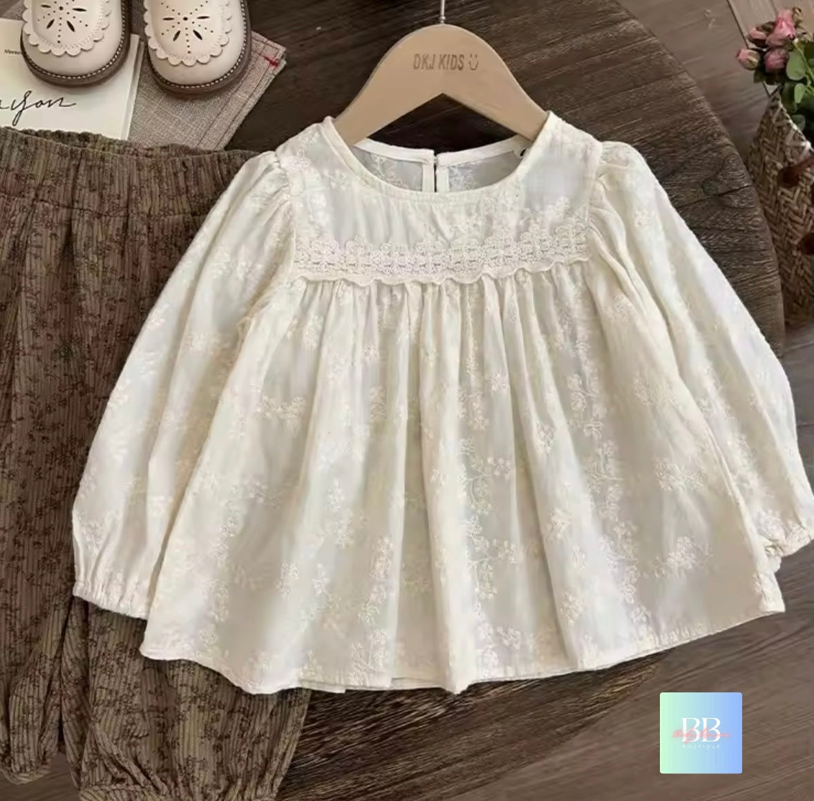White lace baby dress on a wooden hanger with a blurred background