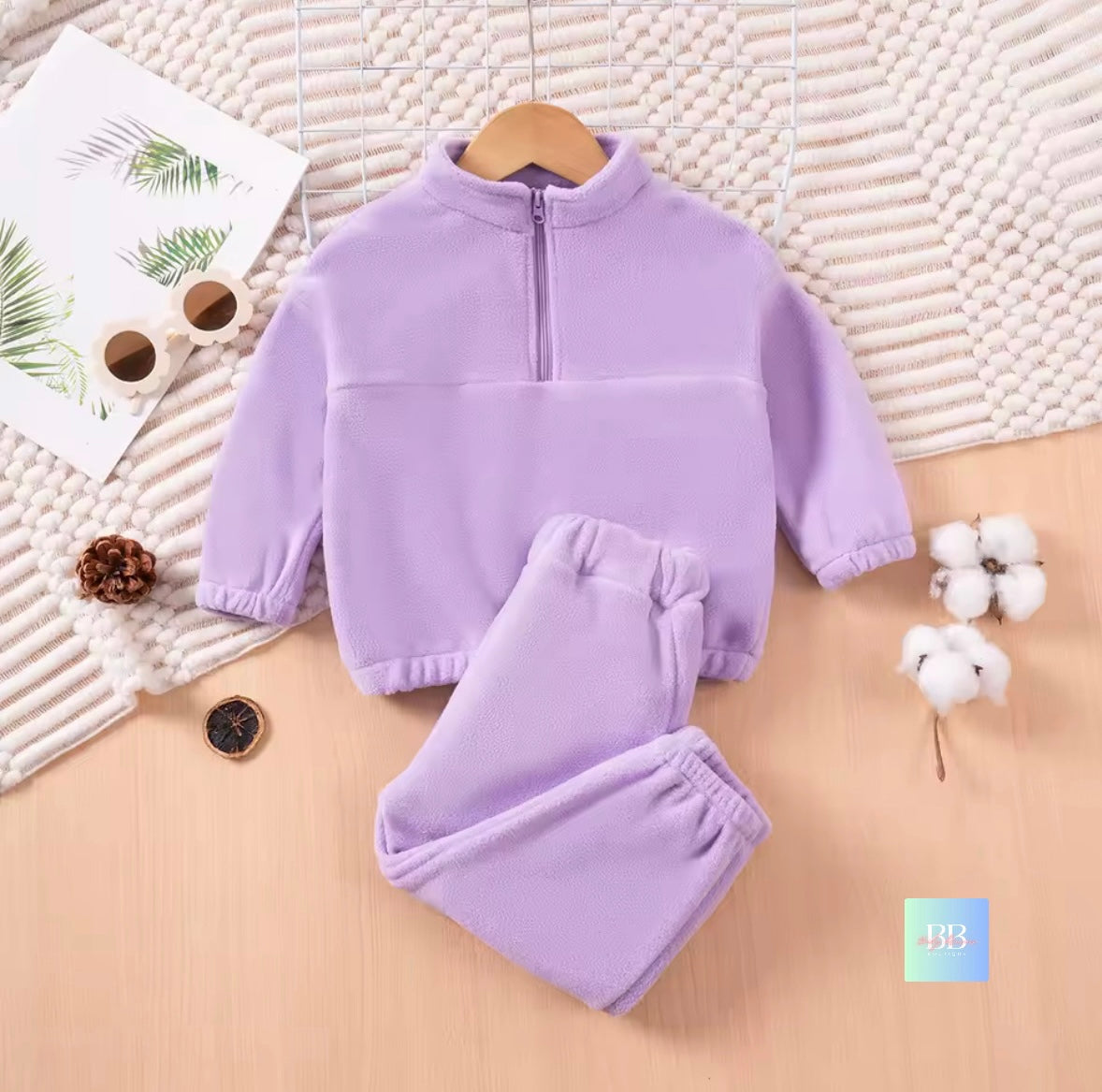 Purple children's outfit on a wooden hanger with a textured background