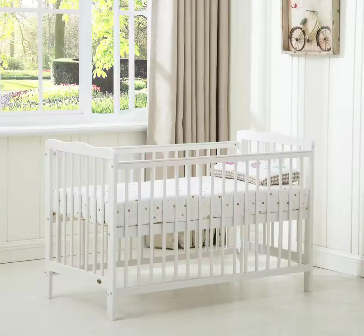 White crib in a bright room with large windows and curtains.