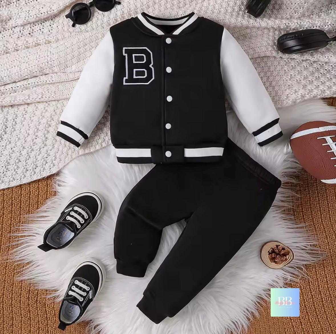 Black and white varsity jacket with 'B' logo on a textured surface with accessories.