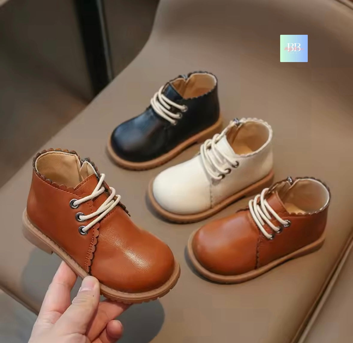 Four pairs of children's leather shoes in different colors on a neutral background.