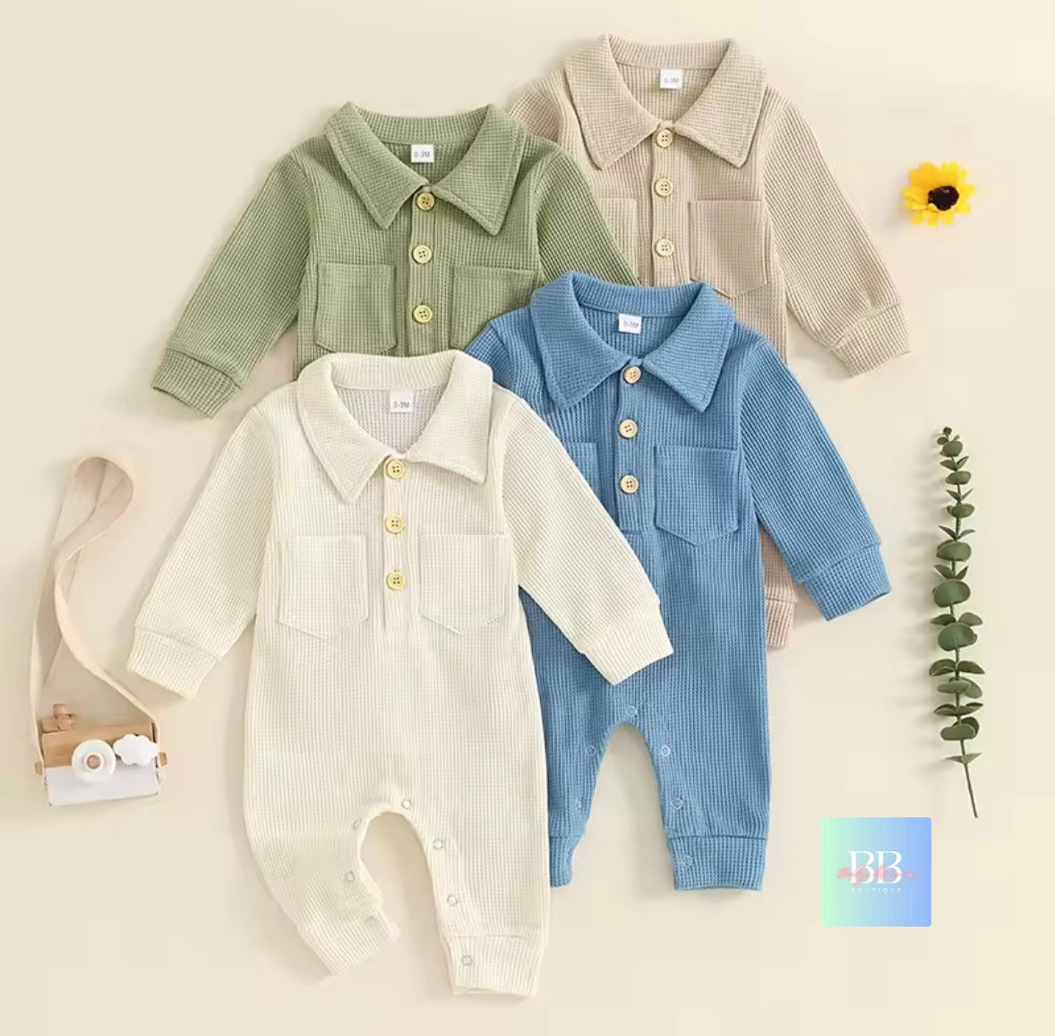 Four baby rompers in green, beige, white, and blue on a light background with a sunflower and eucalyptus leaf.