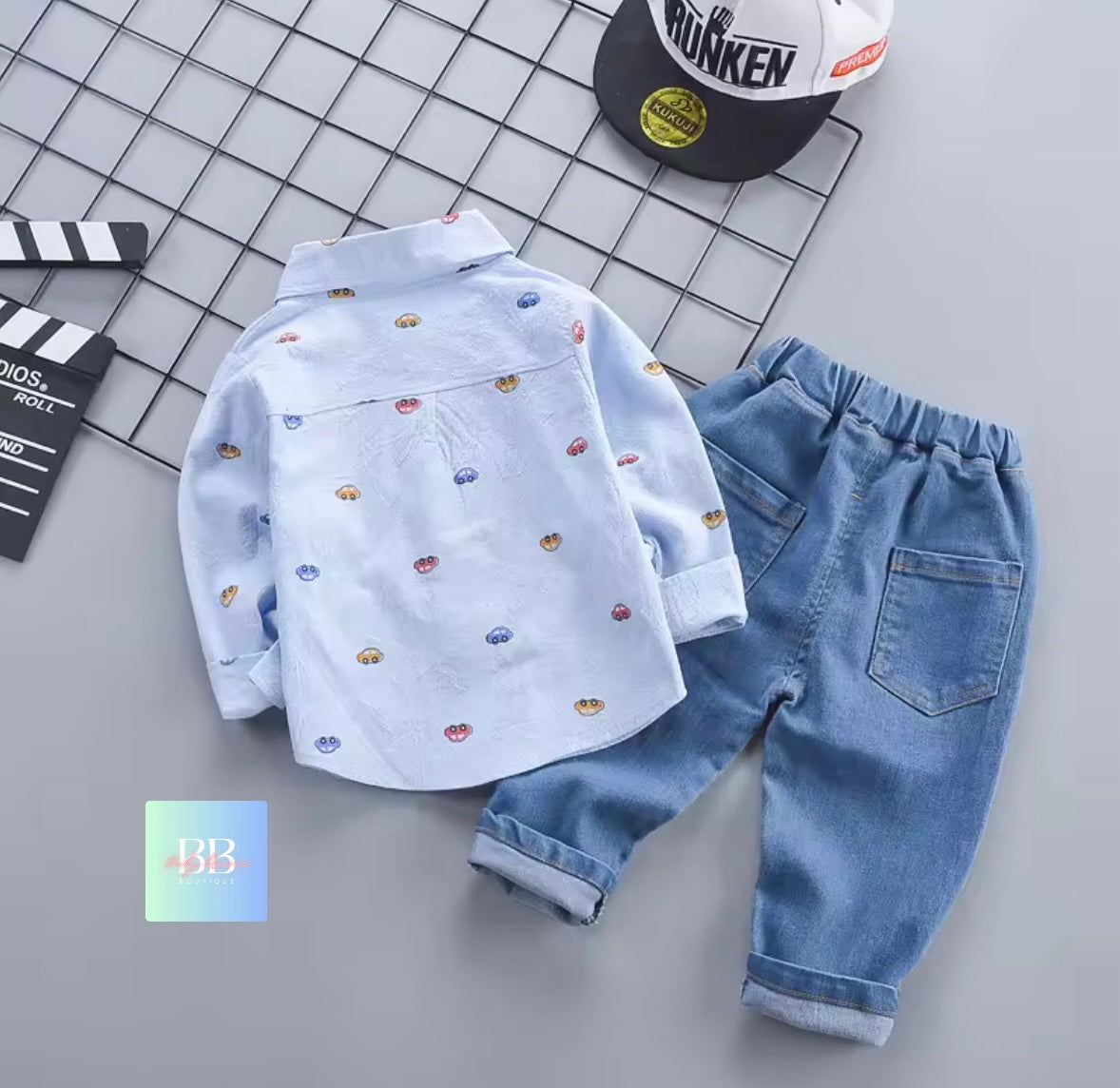 Children's blue shirt with car pattern and jeans on a grid background