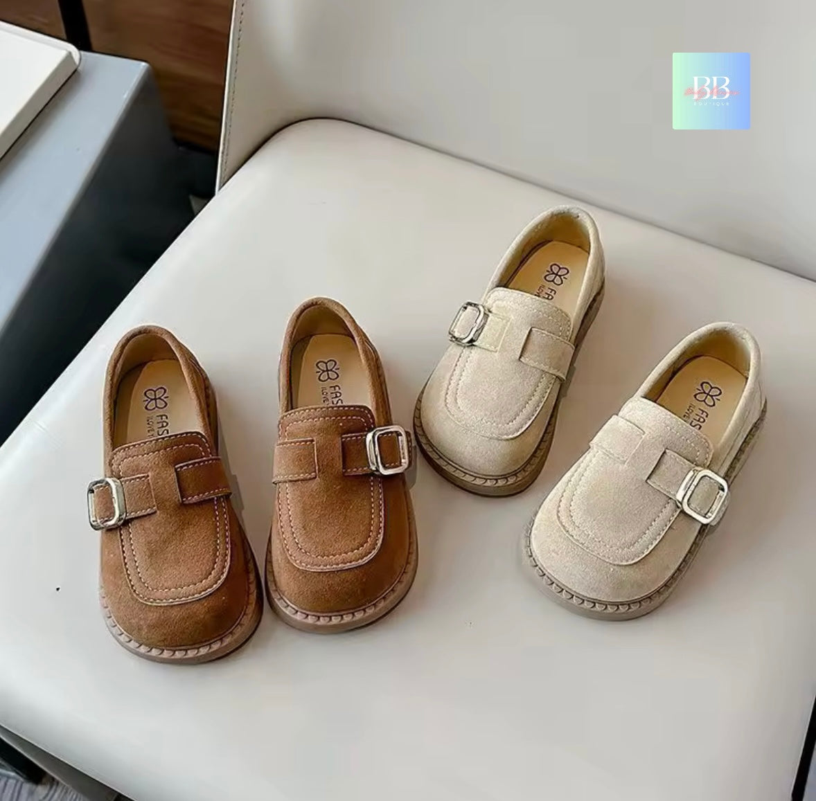 Pair of brown and beige children's shoes with buckles on a white surface.