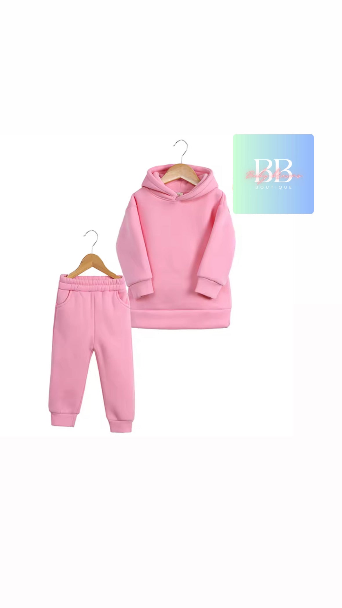 Pink hoodie and pants set on hangers with a brand logo in the corner.