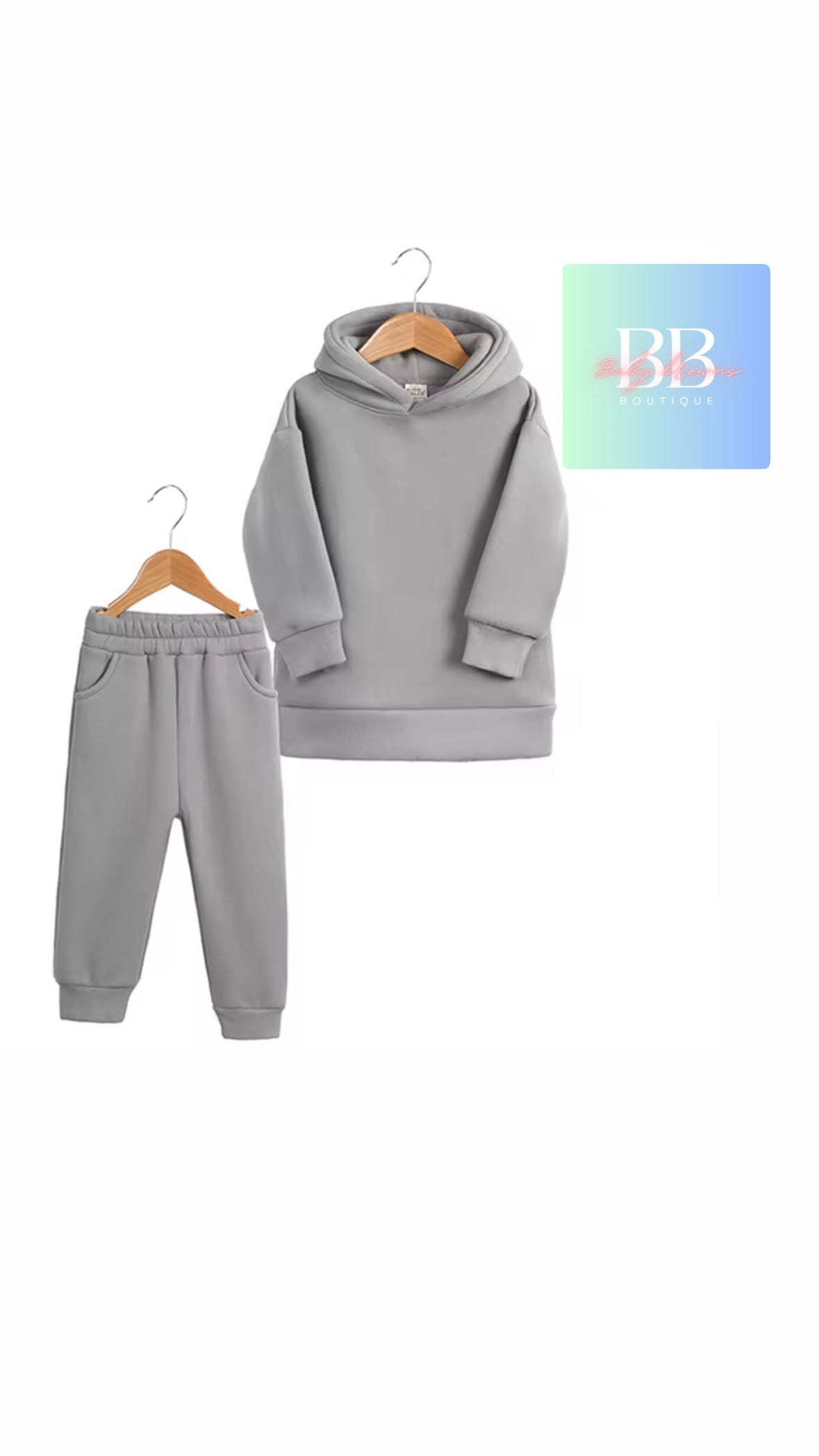 Gray hoodie and pants set on hangers with a brand logo in the corner.