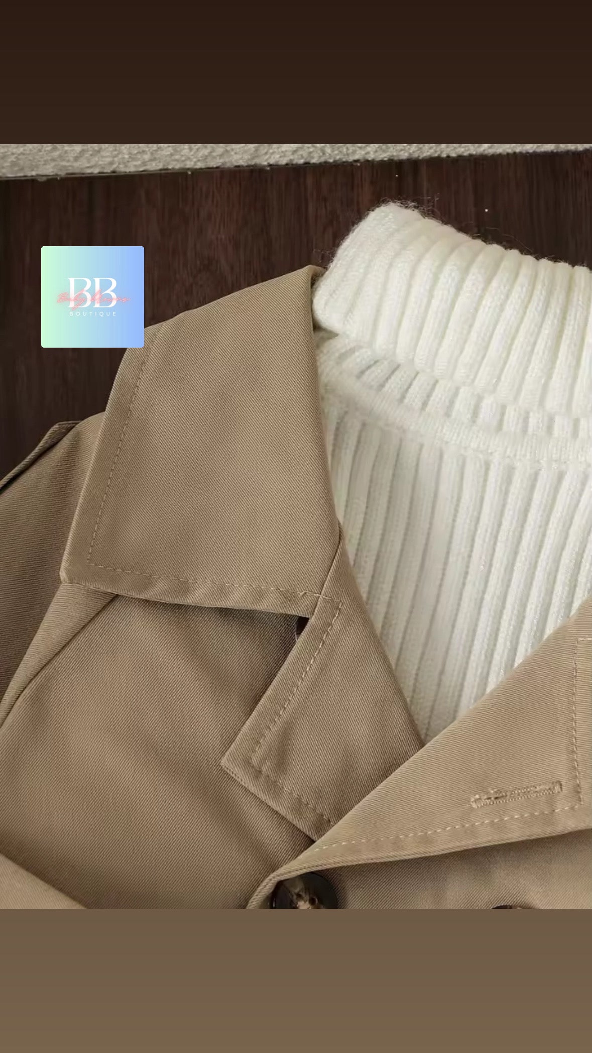 Close-up of a beige trench coat with a white textured pillow against a wooden background