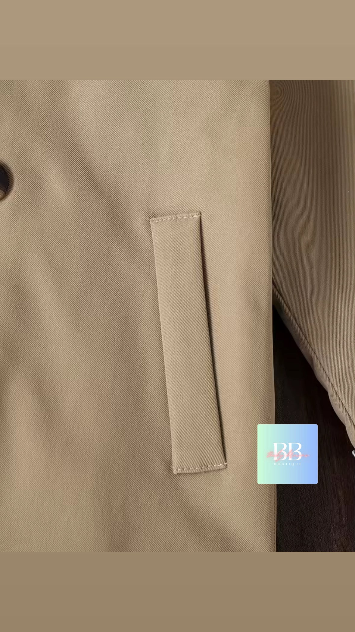 Close-up of a beige coat with a pocket and a visible brand label.