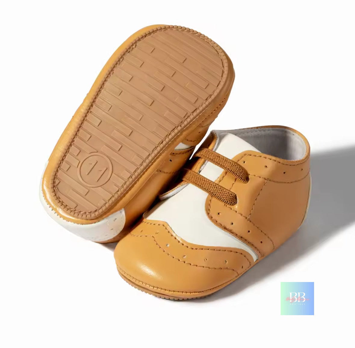 Pair of brown and white baby shoes on a light background