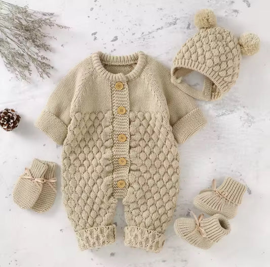 Knitted baby romper with hat, mittens, and booties on a light background