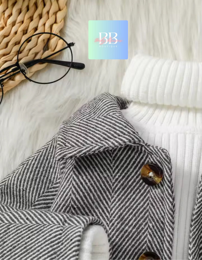 Gray herringbone coat with a button on a textured surface, featuring a brand logo in the corner.