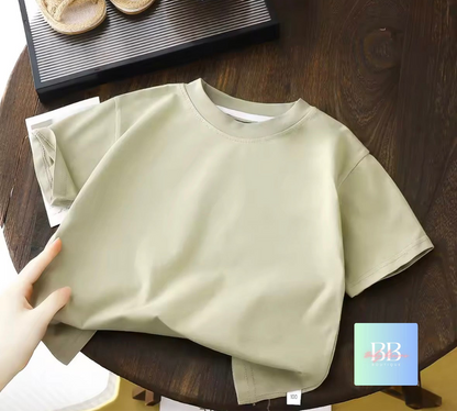 Beige t-shirt on a wooden table with a hand holding it