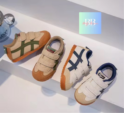 Three pairs of children's shoes on a white surface with a brand logo in the corner.