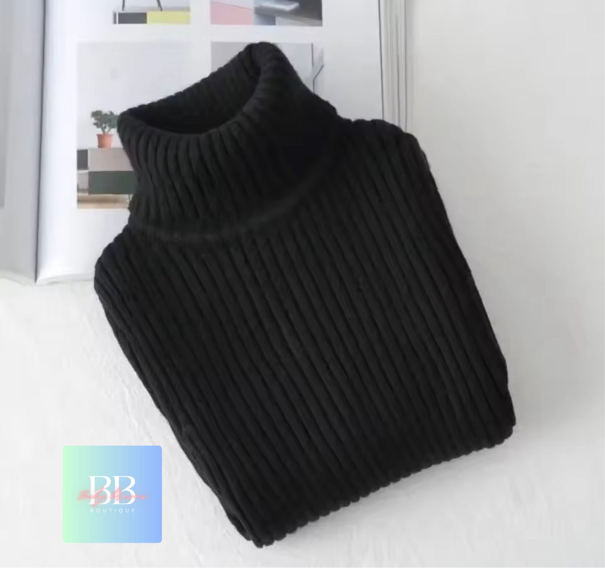 Black turtleneck sweater on a white surface with a blurred background