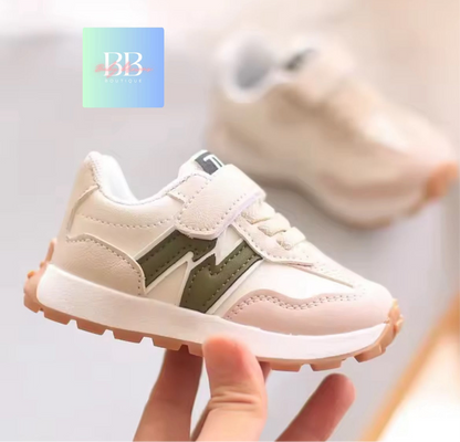 Baby shoe with green accents held by a hand, brand logo visible