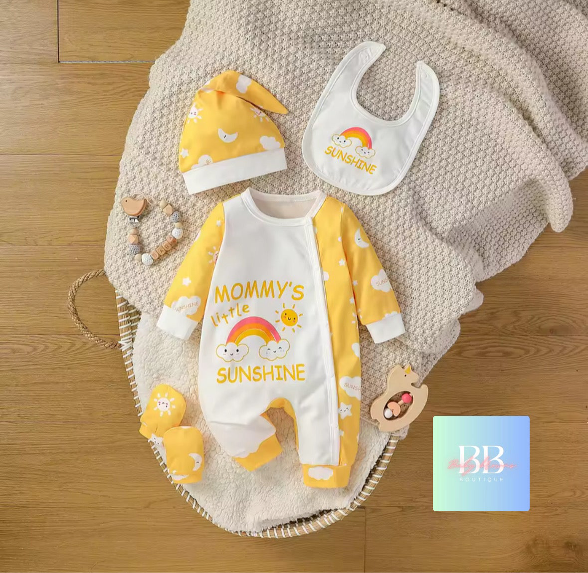 Baby outfit set with 'Mommy's Little Sunshine' design on a wooden surface.