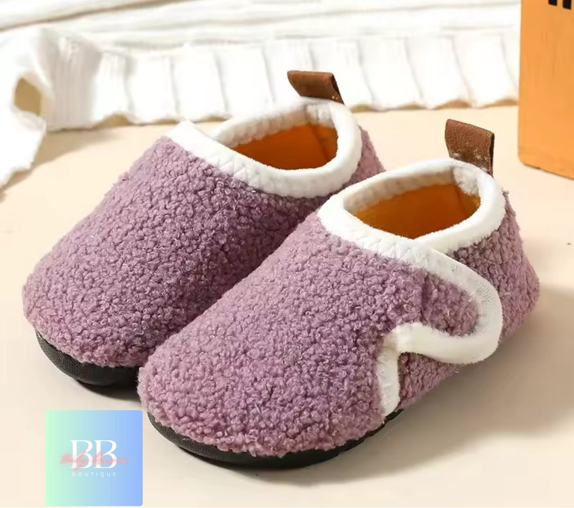 Pair of purple slippers with white trim on a light background