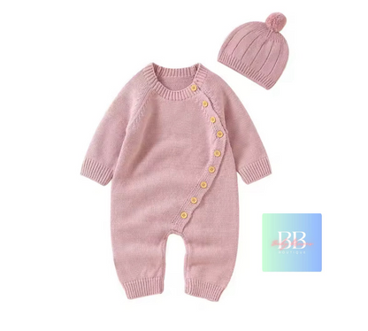 Pink knitted baby romper with buttons and matching hat on a white background