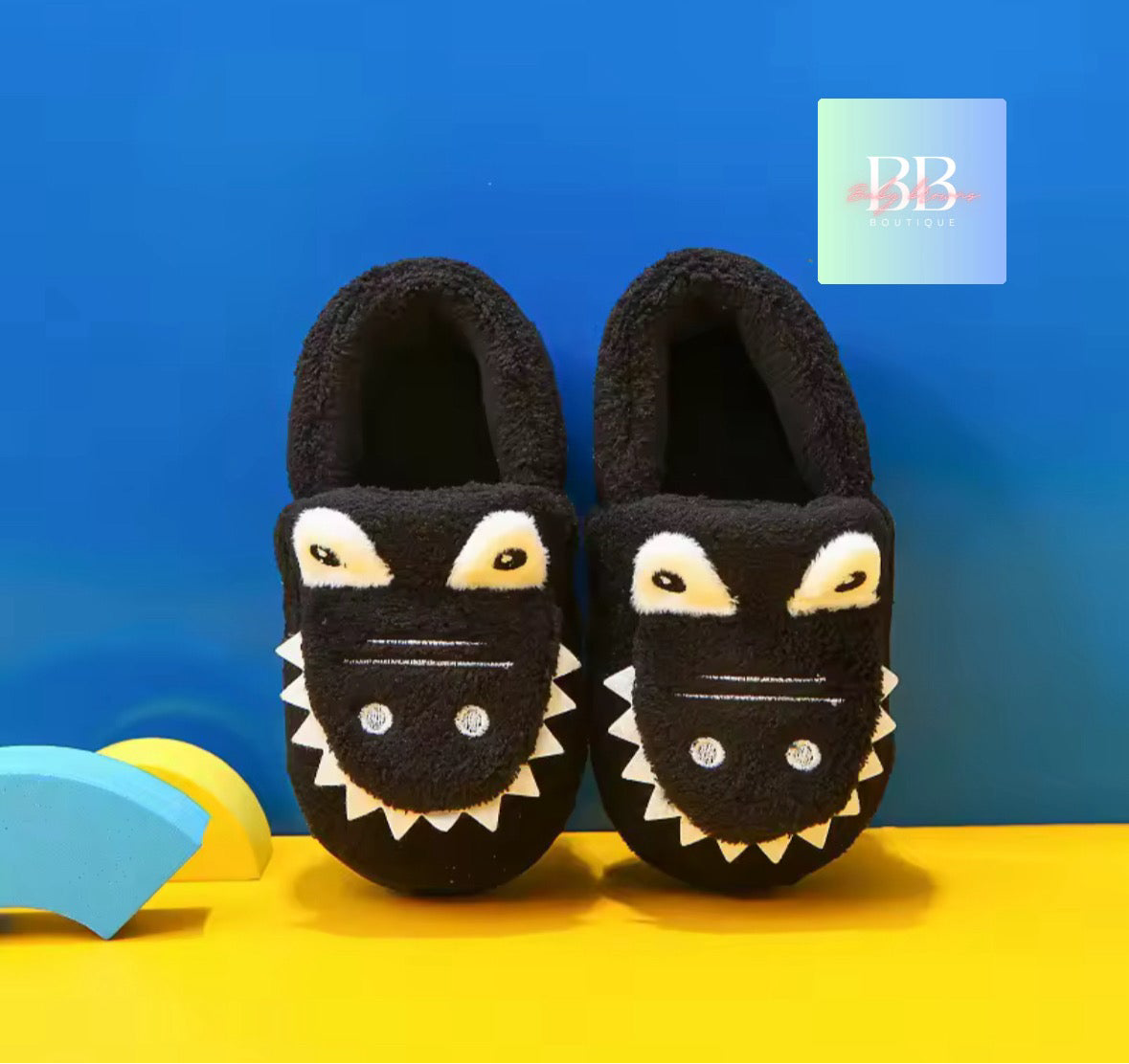 Black shark-themed slippers on a yellow surface with a blue background