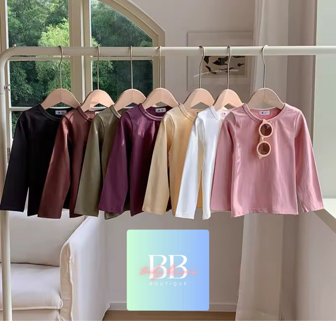 Row of colorful long-sleeve shirts on hangers with a visible brand logo in the background.