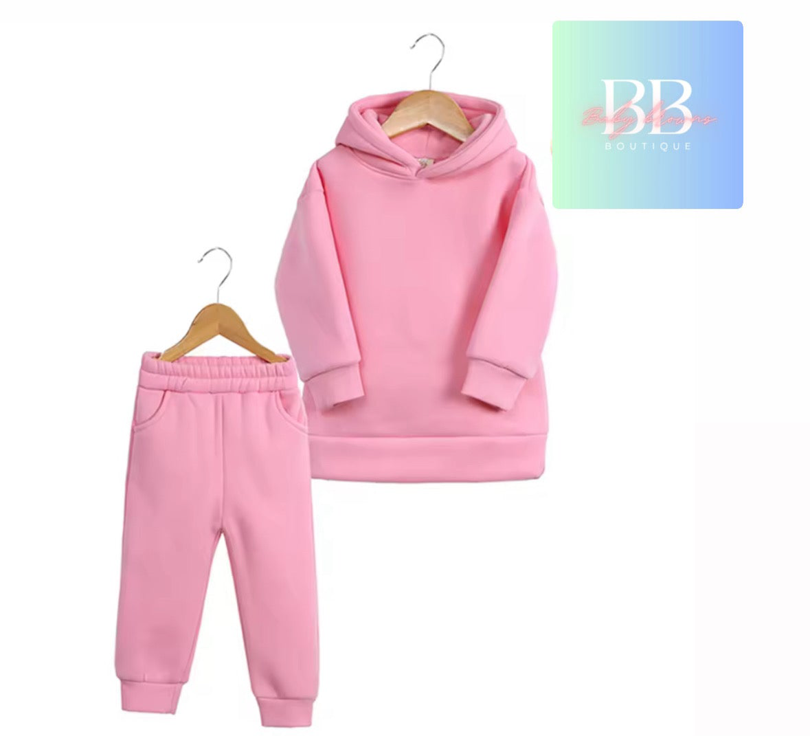 Pink hoodie and pants set on hangers with a brand logo in the corner.