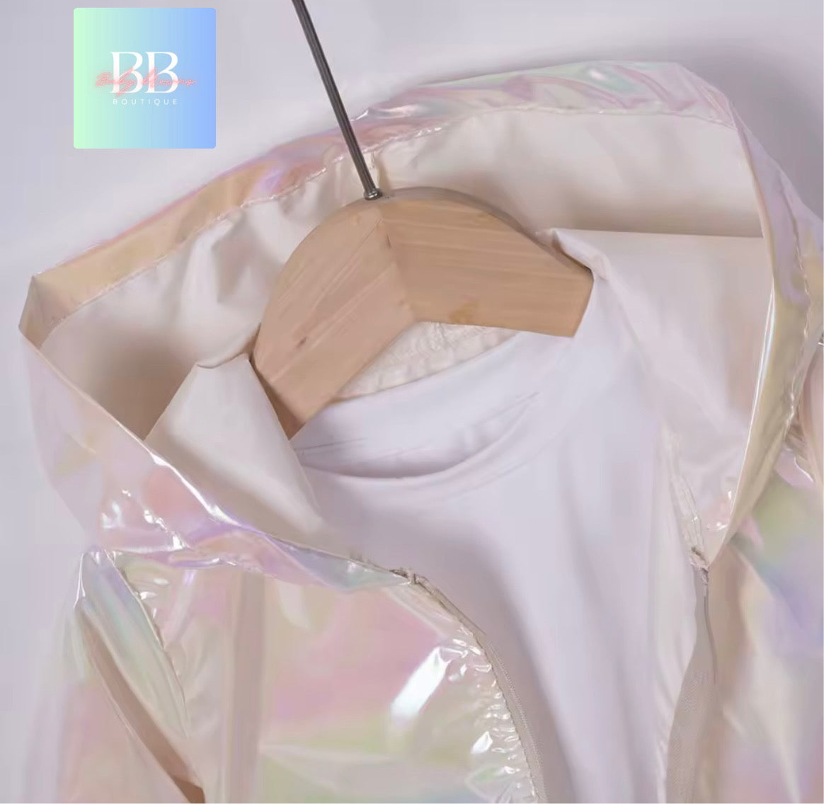 White top with iridescent sheen on a wooden hanger against a white background
