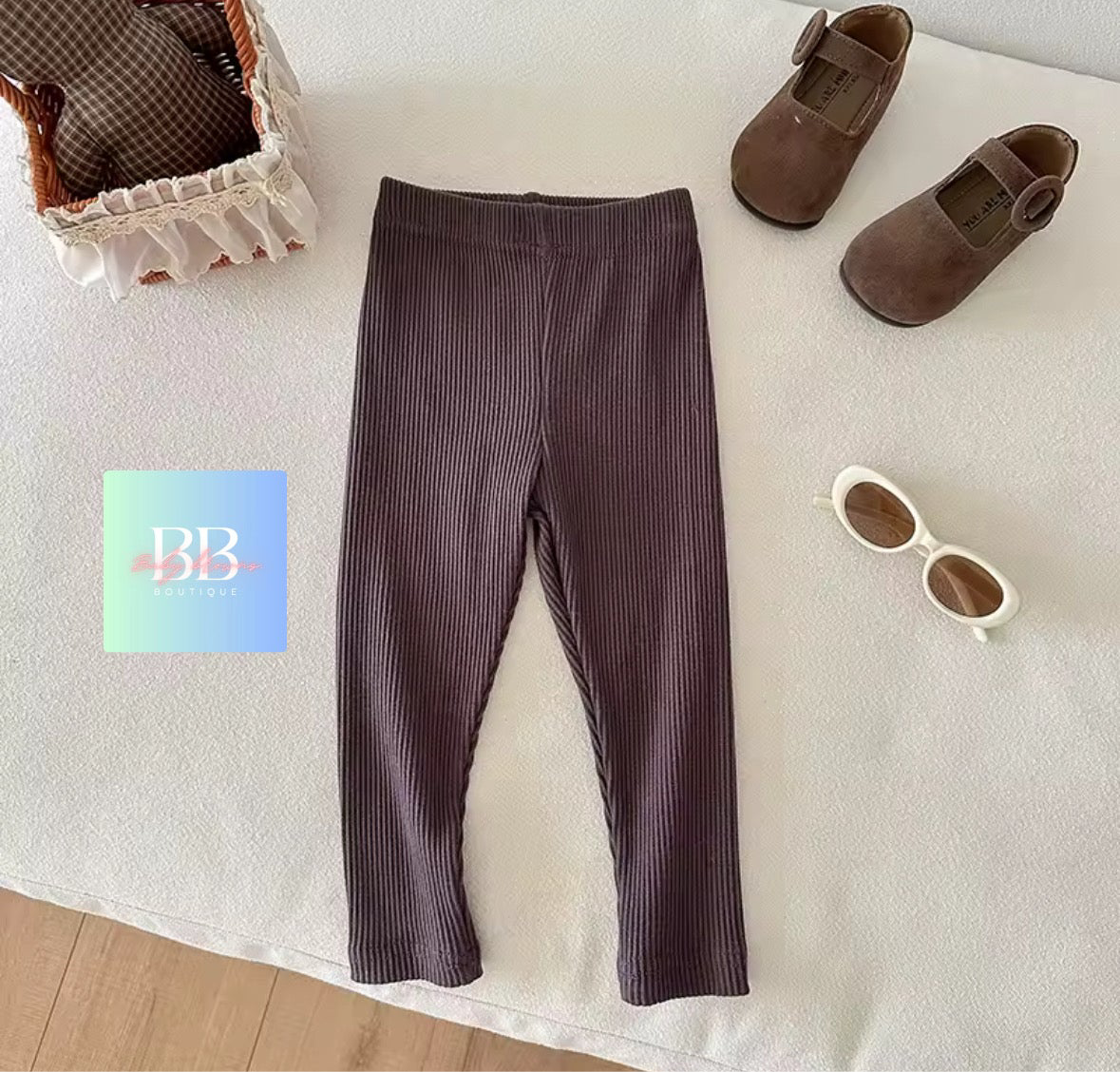 Brown ribbed leggings on a white surface with shoes and sunglasses nearby.