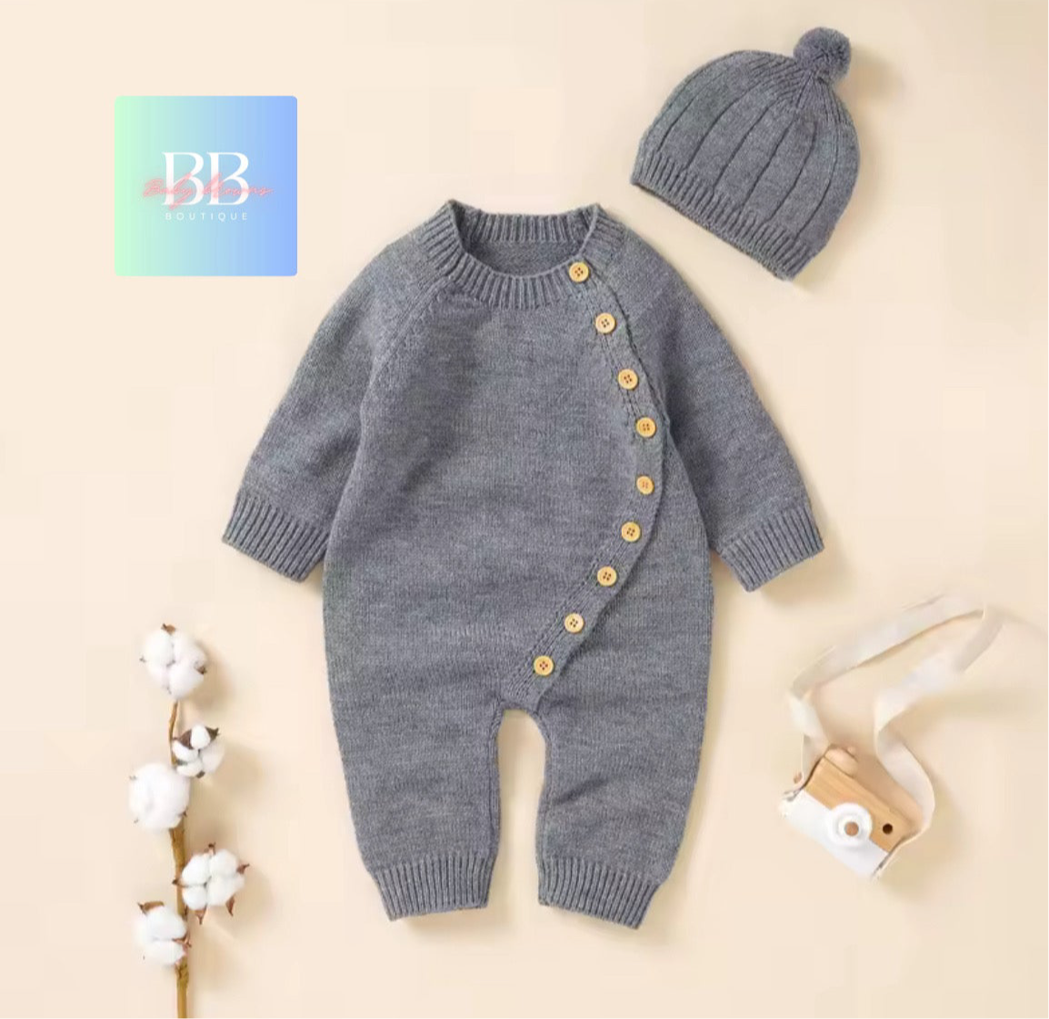Gray knitted baby romper with buttons and matching hat on a beige background, featuring a brand logo.