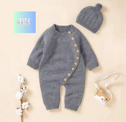 Gray knitted baby romper with buttons and matching hat on a beige background, featuring a brand logo.