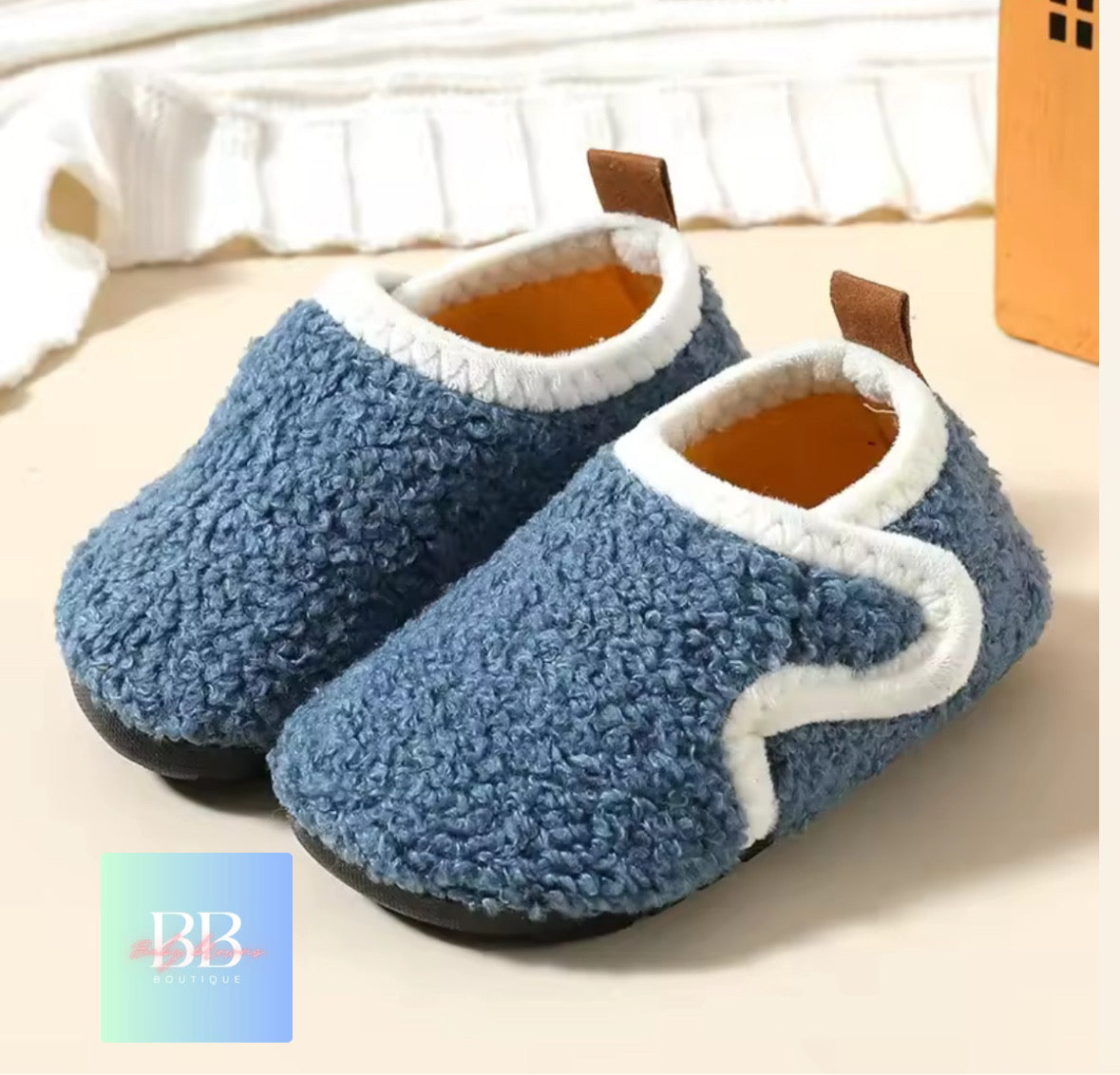 Pair of blue fuzzy slippers with white trim on a light background