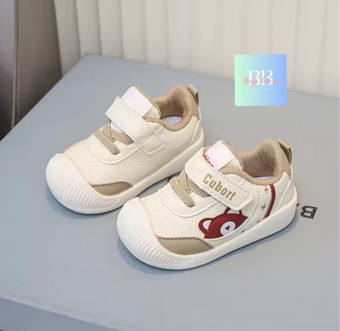 Pair of children's shoes with a visible brand logo on a gray surface.