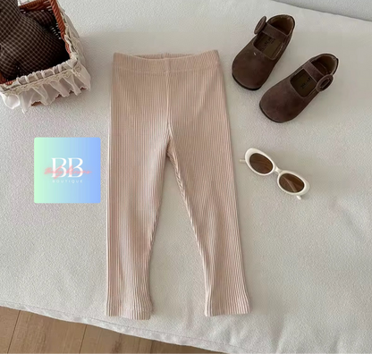 Beige leggings with brown shoes and sunglasses on a light surface, with a card featuring 'BB' branding.