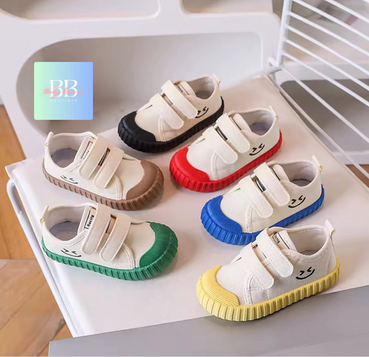 Set of colorful children's shoes with smiley face design on a white surface.