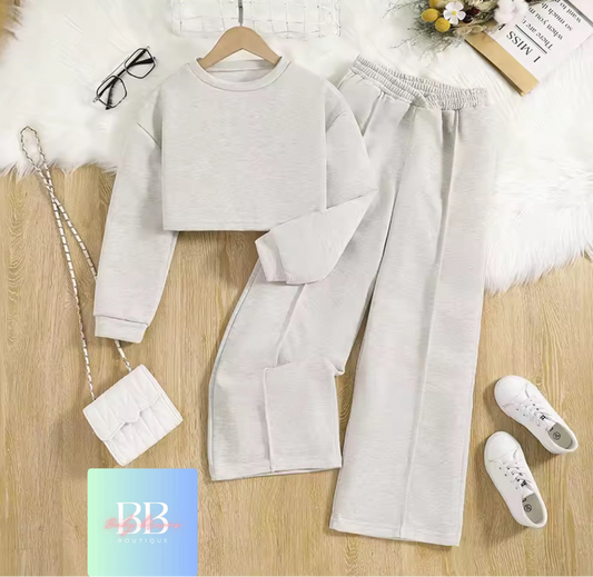 Light gray sweatshirt and pants set with white sneakers and handbag on a wooden surface.