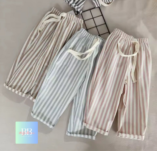 Three pairs of striped pants on a grid background with a brand logo in the corner.