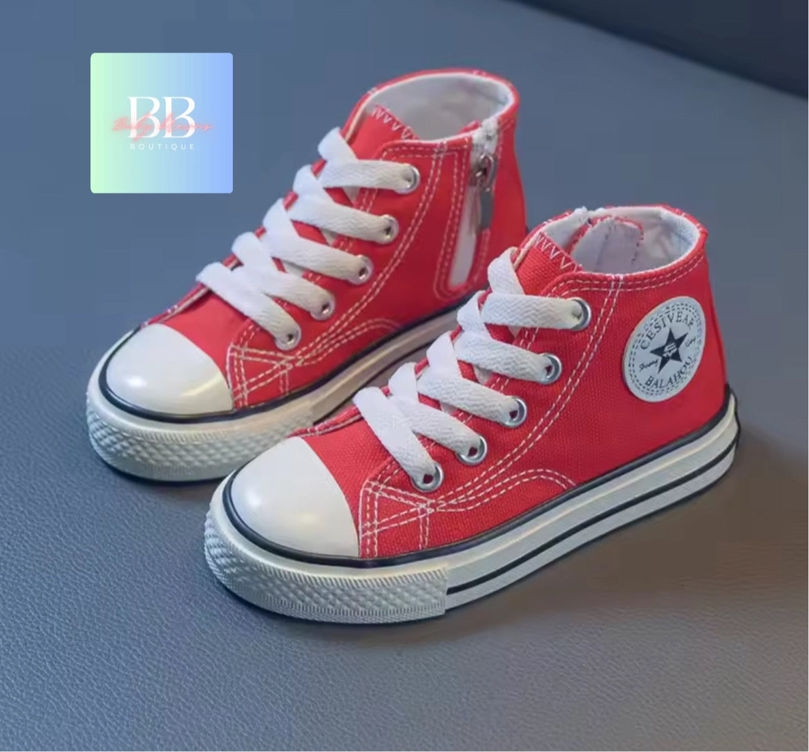 Red high-top sneakers with white laces on a gray surface, featuring a brand logo in the corner.
