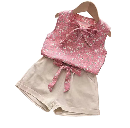 Pink floral top with a bow and beige shorts on a white background