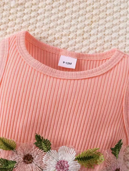 Pink ribbed sweater with floral and leaf patterns on a textured beige background