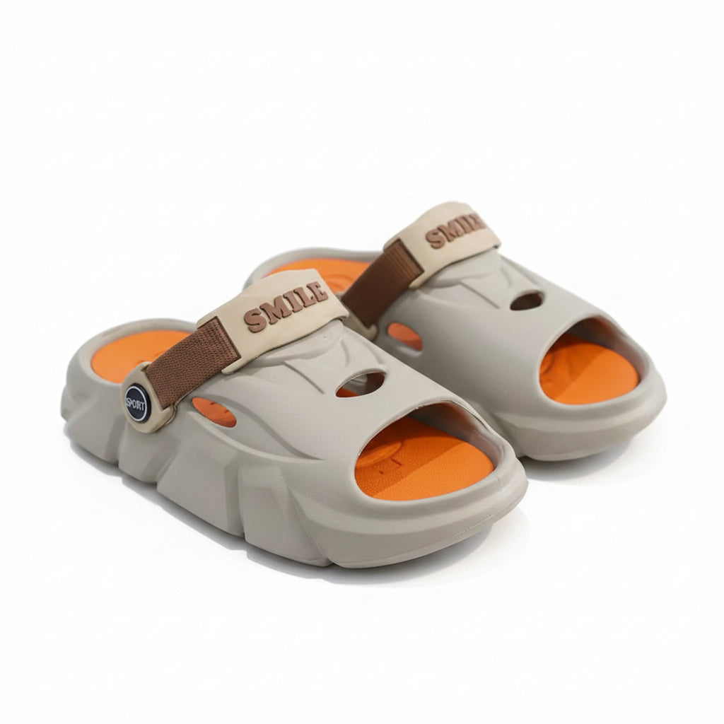 Pair of gray sandals with orange soles and brown straps on a dark surface.