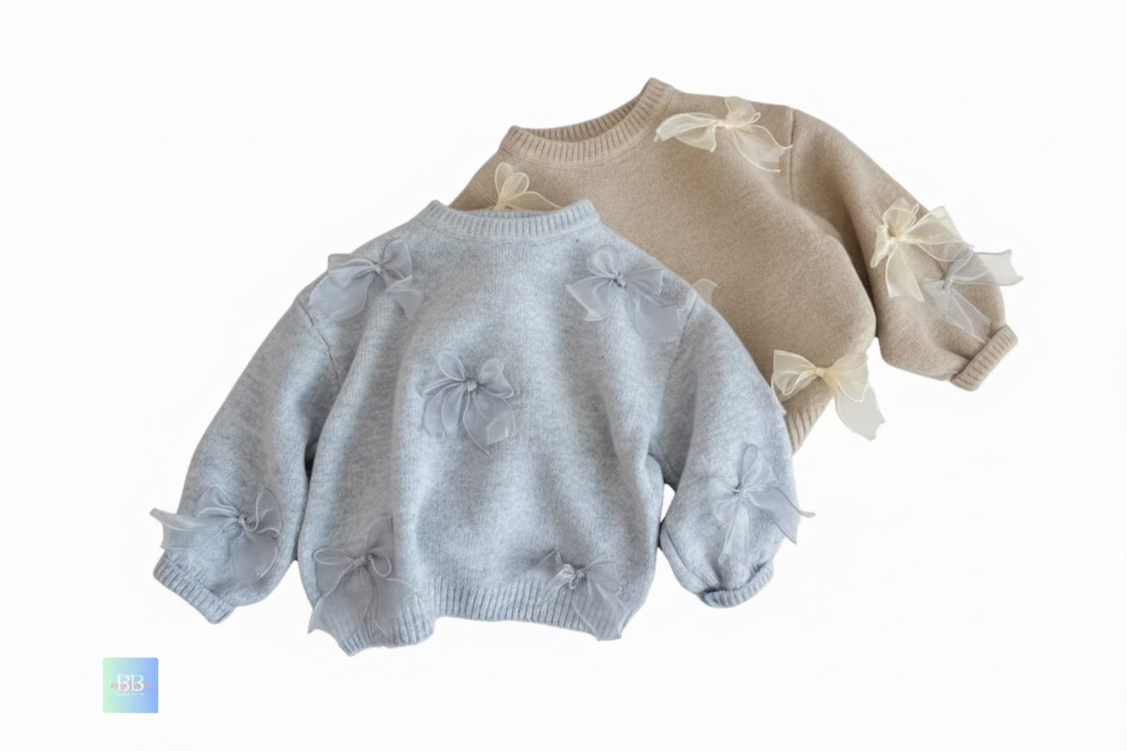 Light gray sweater with bow details on a wooden surface
