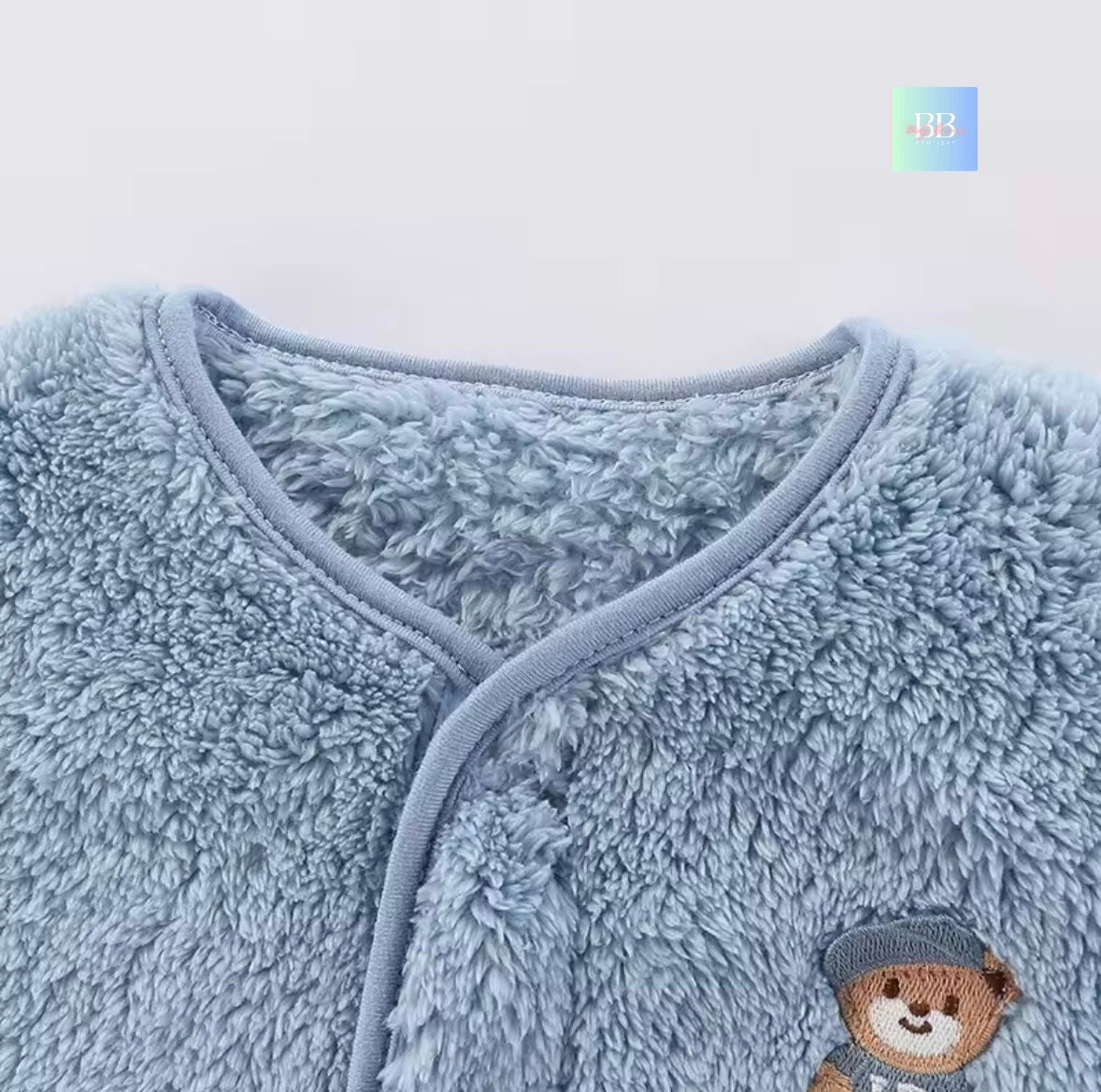 Close-up of a blue fluffy garment with a teddy bear design on a white background