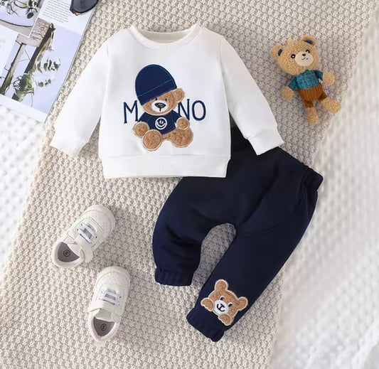 Children's outfit with white shirt, navy pants, and teddy bear design on a textured surface.
