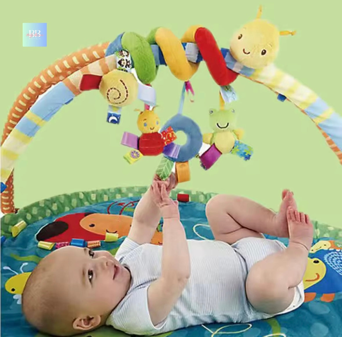 Baby playing with a colorful baby gym on a green background