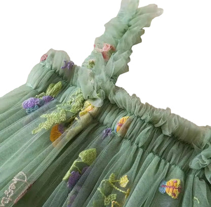 Green embroidered dress with floral details on a textured beige background