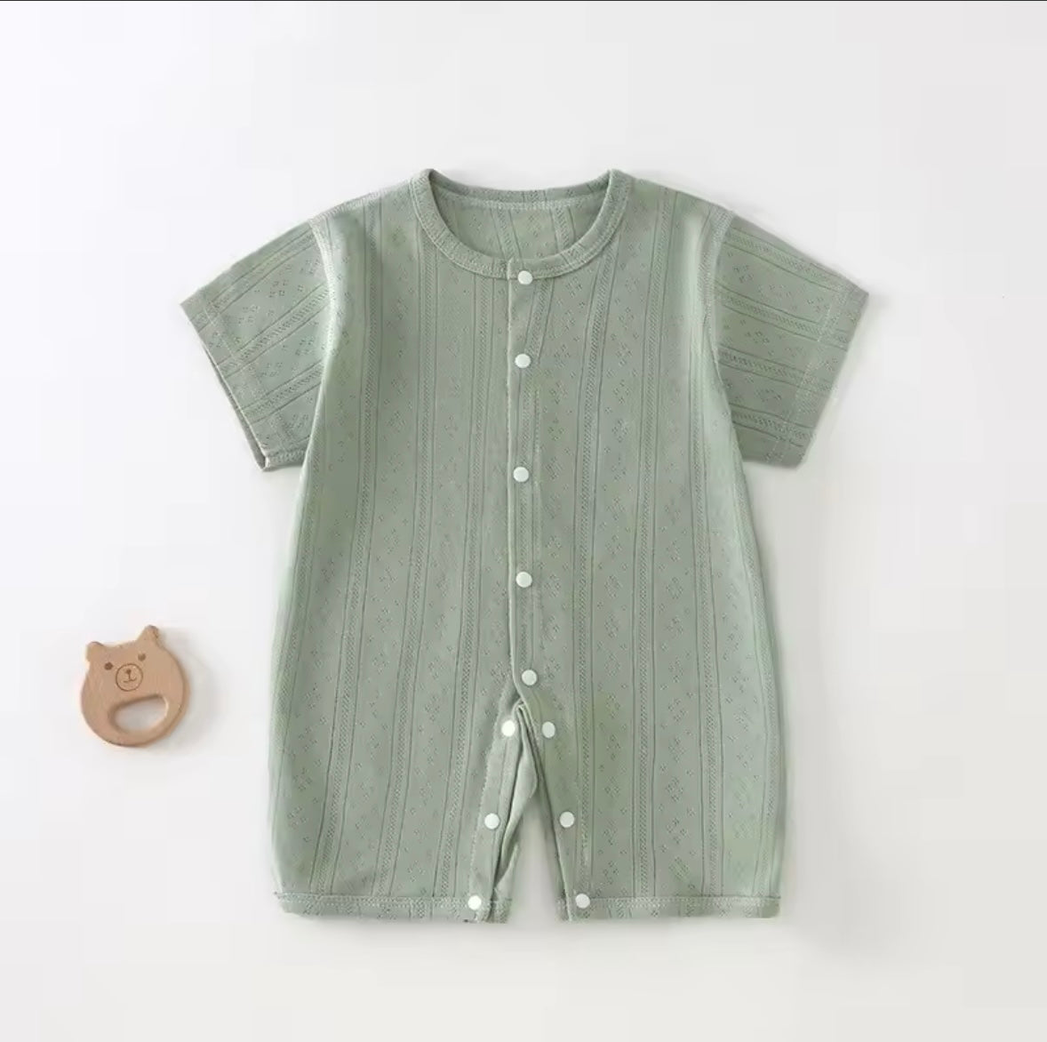 Green baby romper with buttons on a white background