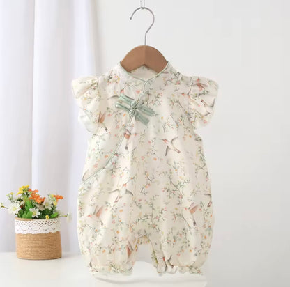 Floral baby romper on a hanger against a white background
