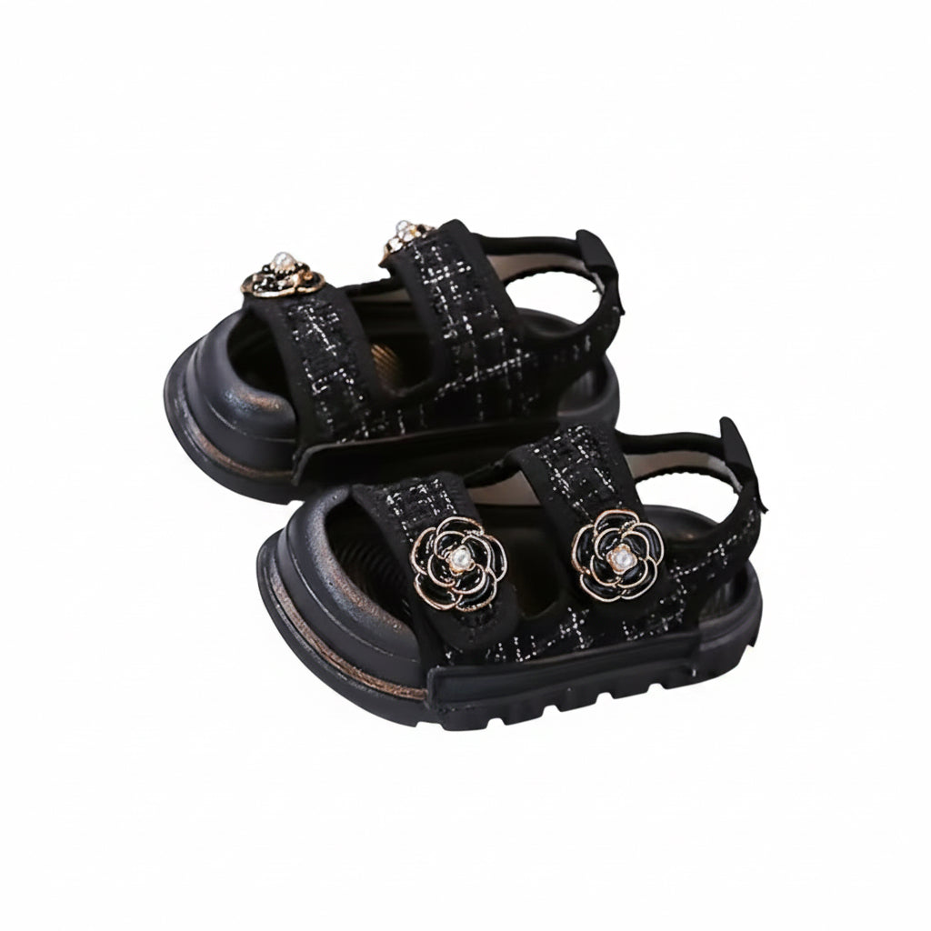 Black sandals with decorative elements on a gray surface