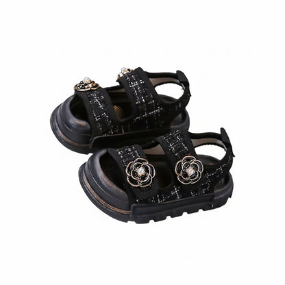 Black sandals with decorative elements on a gray surface