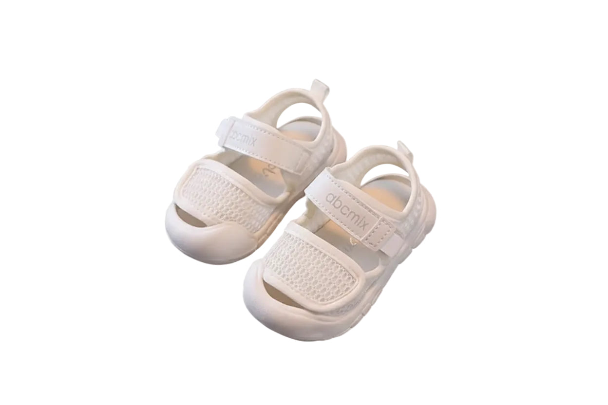 White baby sandals on a beige chair